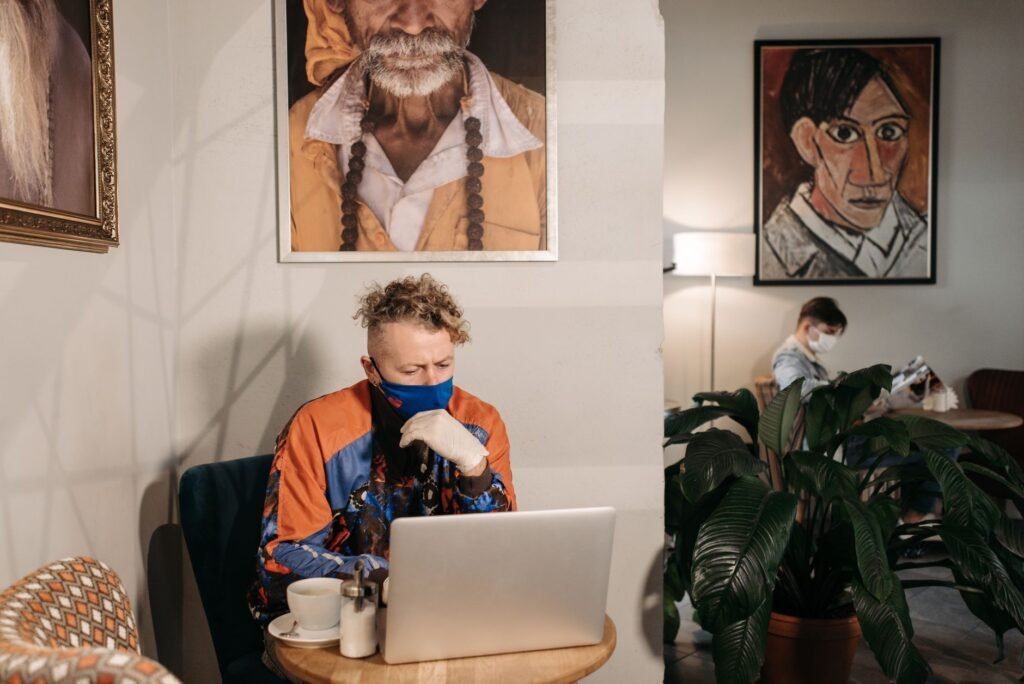 Henkilö selaamassa hakemistoa kannettavalla tietokoneella kahvilassa