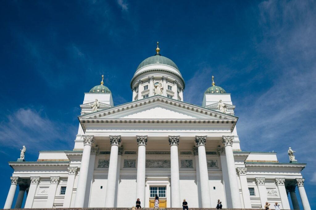 Helsingin katedraalin etunäkymä kirkasta sinistä taivasta vasten, korostaen neoklassista arkkitehtuuria.
