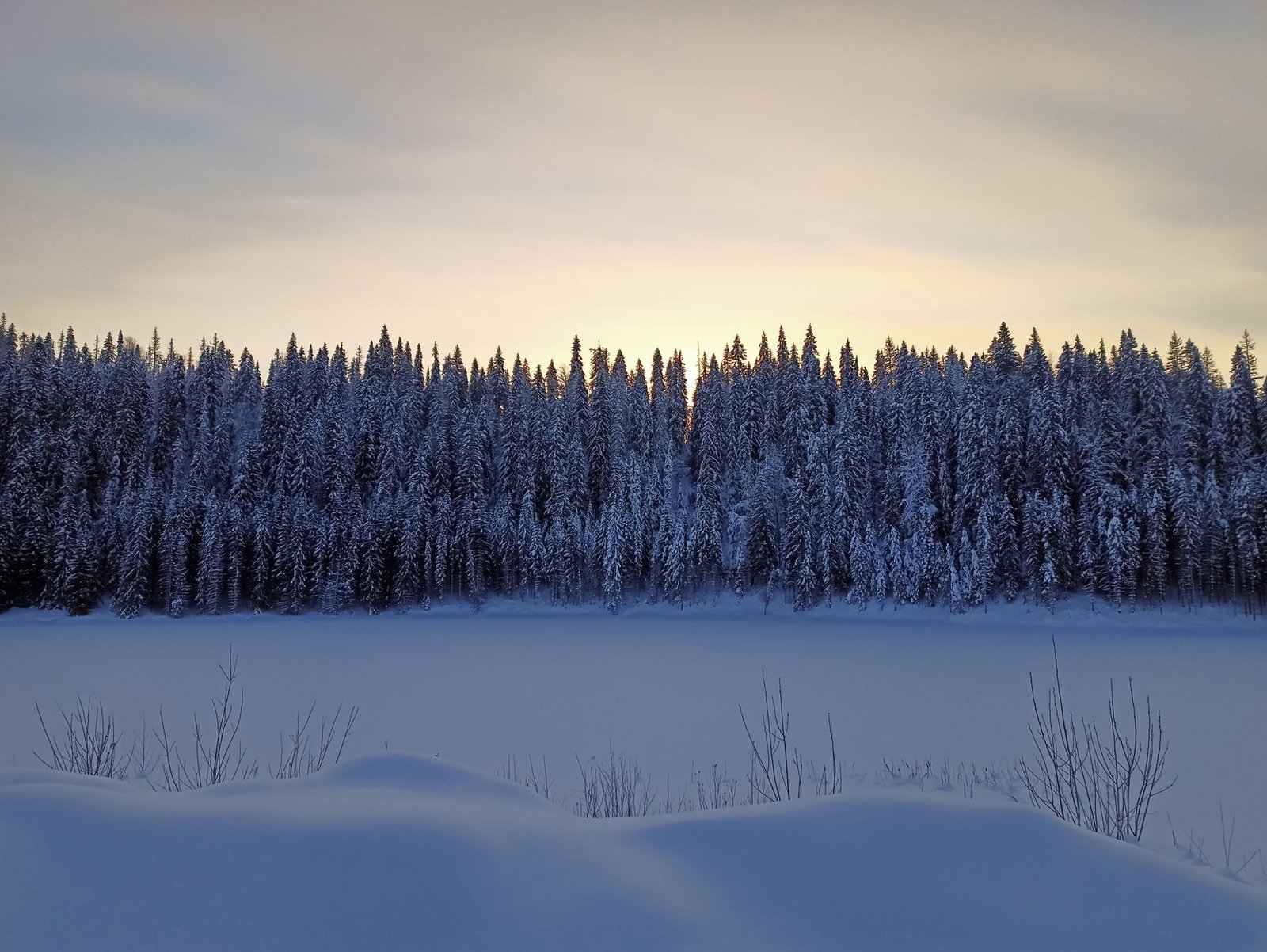 Talvinen ilta Kuusamossa, lunta ja lämmin valo ikkunasta