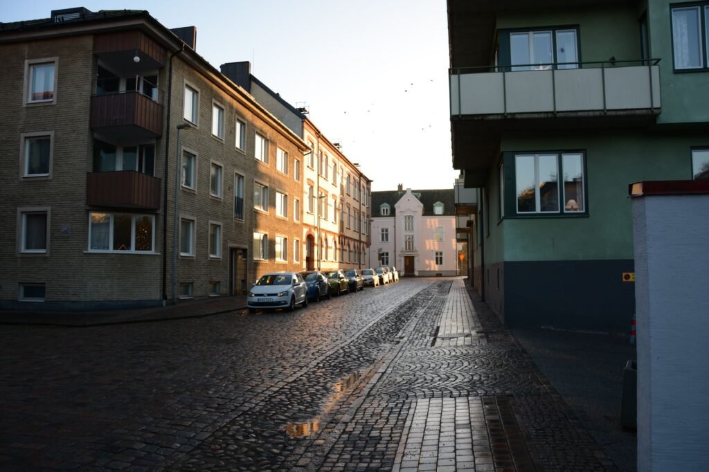 Mukulakivikatu pysäköityjen autojen kanssa auringonlaskun aikaan eurooppalaisessa kaupungissa.