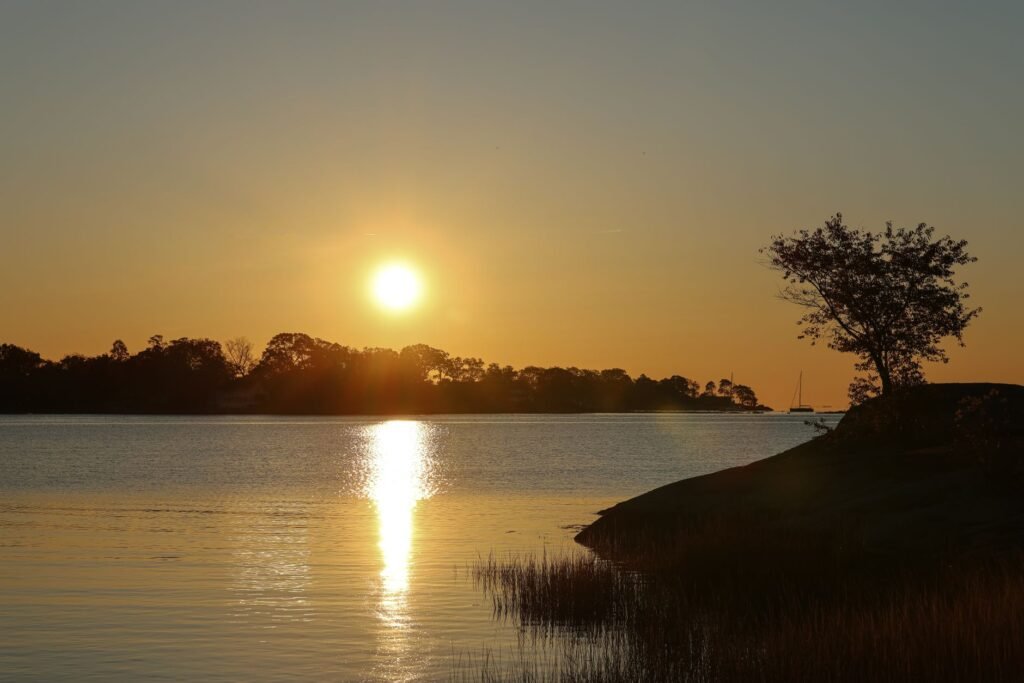 Rauhallinen auringonnousu veden yllä Cove Island Parkissa Stamfordissa, esittäen syksyn kauneuden.