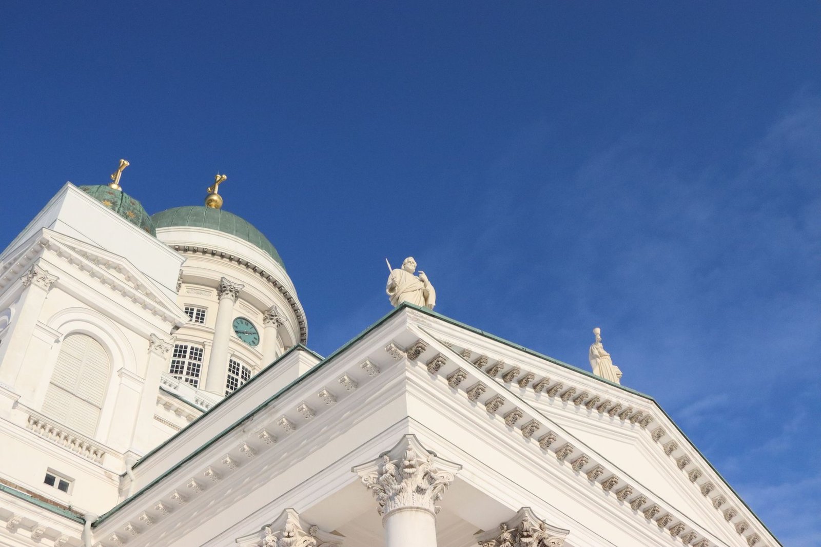 Alhainen näkymä Helsinki Katedraalin neoklassisesta julkisivusta kirkasta sinistä taivasta vasten.