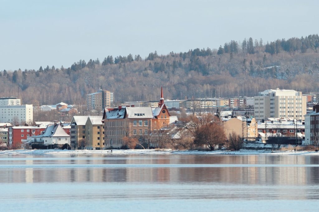 Lumoava talvikaupunki Jönköpingissä, Ruotsissa, lumipeitteisten rakennusten kanssa järven rannalla.