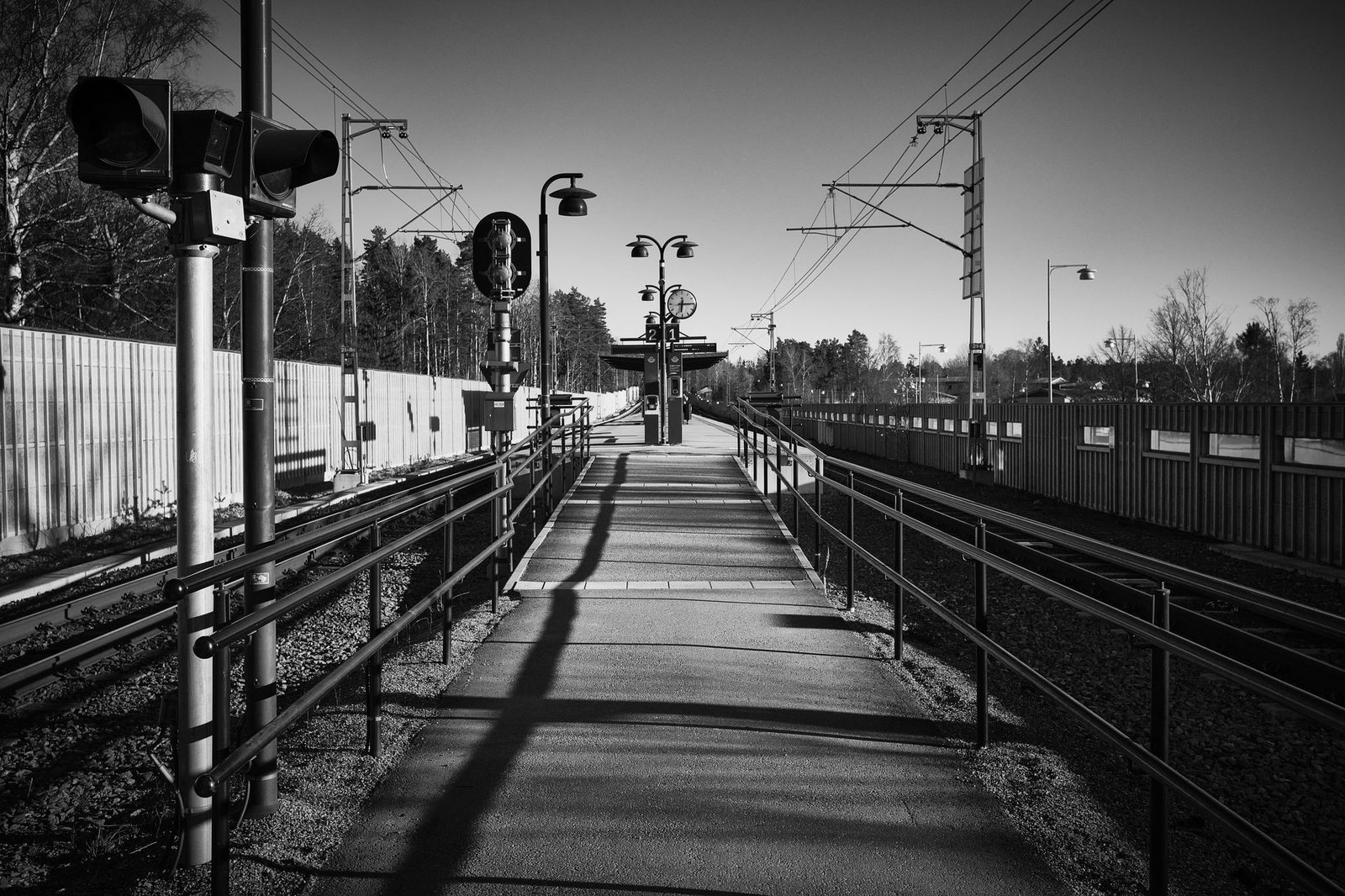 Rauhallinen junalaituri Pieksämäellä iltapäivän valossa, matkalaukku vieressä