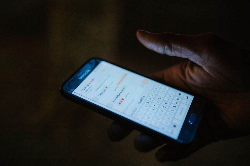 Kädet kirjoittamassa viestiä puhelimella illalla