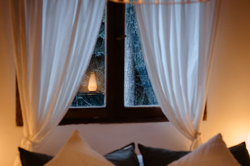 Hotellihuone Rovaniemellä talvi-iltana, lämmin valaistus ja luminen maisema ikkunasta