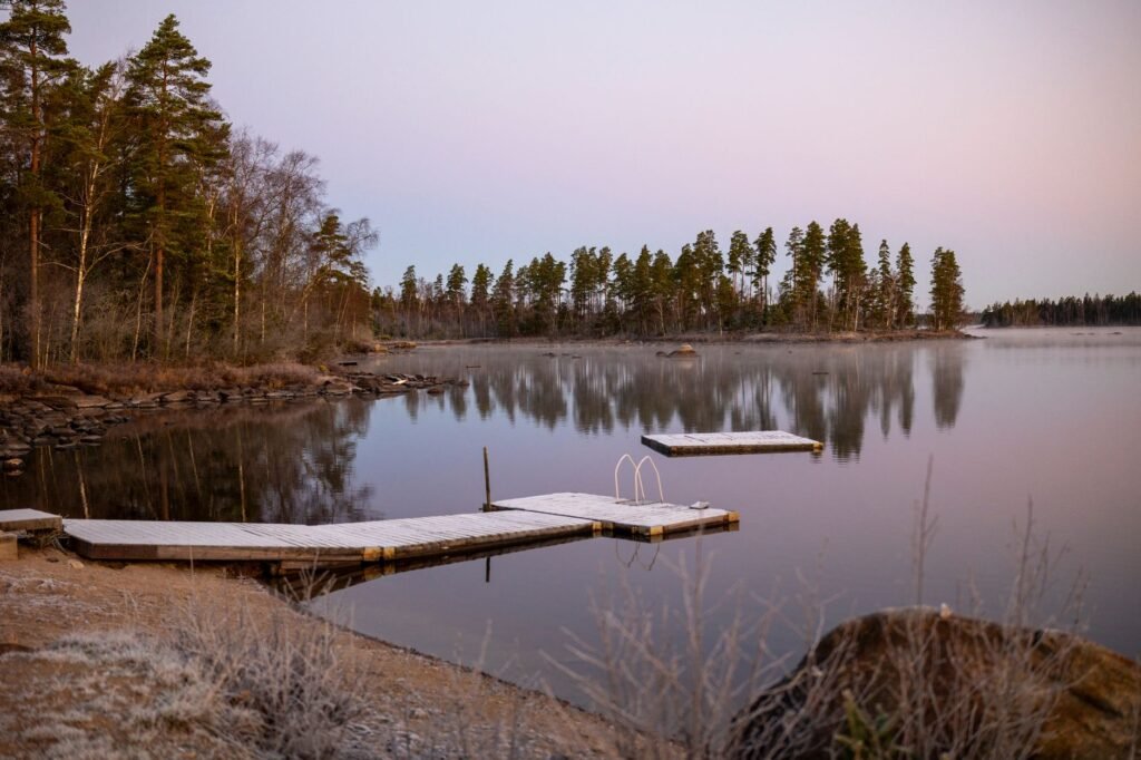 Rauhallinen järvisivu, jossa on huurteiset laiturit hämärässä, vangitsevalla rauhallisella talviilmapiirillä.